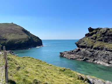 A coastal scene with rocky cliffs and green grass overlooking the sea at Harbour Light Boscastle