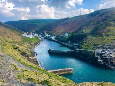 A coastal village with houses along a narrow inlet surrounded by hills and stone piers at Harbour Light in Boscastle