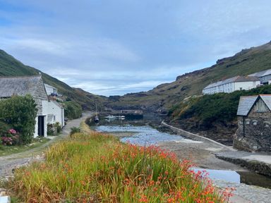 A coastal village with houses along a narrow harbor and boats in the water at Harbour Light in Boscastle
