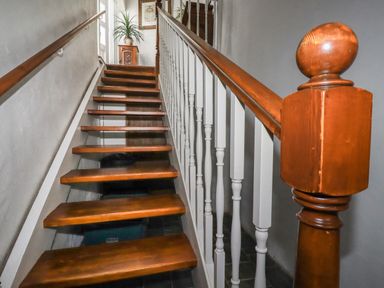 A wooden staircase with white balusters and handrails leading to a small cabinet with a plant on top at Harbour Light in Boscastle