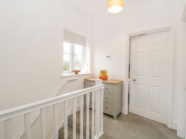 A landing area with a window a grey chest of drawers and a white door at The Hollies in Norwich