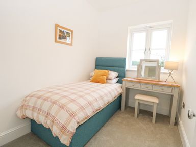 A bedroom with a single bed a dressing table with stool lamp and mirror at The Hollies in Norwich