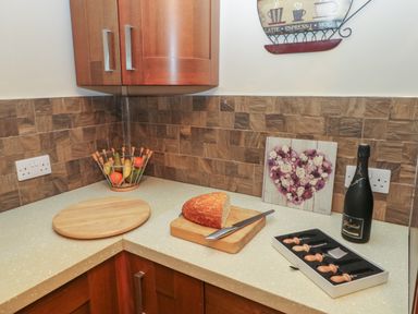 A kitchen corner with wooden cabinets fruit bowl cutting boards bread knife and a bottle at Garden View in Pembroke