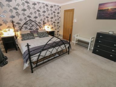 A bedroom with a metal bed frame two bedside tables with lamps a chest of drawers and a bench at Garden View in Pembroke