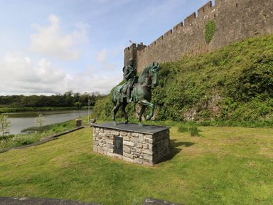 A statue of a knight on a horse near a stone wall with greenery and a body of water at Garden View in Pembroke