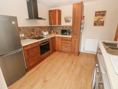 A kitchen with wooden cabinets a stainless steel fridge oven microwave and washing machine at Garden View in Pembroke