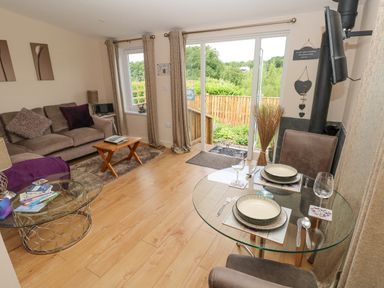 A living room with a sofa coffee tables and a glass dining table near sliding doors at Garden View in Pembroke