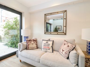 A sofa with three cushions and two table lamps in a living room at Fawcett Cottage in Aldeburgh