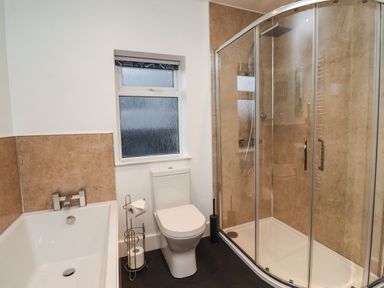 A bathroom with a bathtub toilet and glass shower enclosure at Maywood in Seahouses