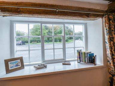 A window sill with a framed picture, decorative items, and books at Lythe Cottage in Lythe