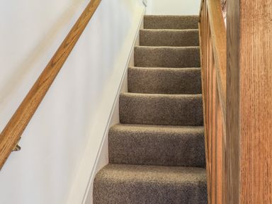 A carpeted staircase with wooden handrails on both sides at Lythe Cottage in Lythe