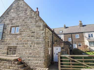 A stone cottage with stairs and flower pots next to a wooden gate at Lythe Cottage in Lythe