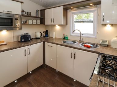 A kitchen with a microwave toaster kettle coffee machine sink and stove at Lakeside Haven in Carnforth