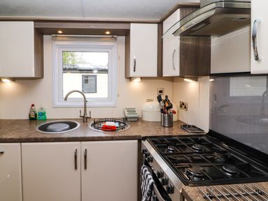 A kitchen with a sink stove countertop cabinets and window at Lakeside Haven in Carnforth