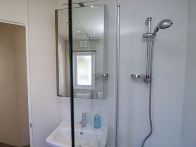 A bathroom with a sink, mirror, and shower at Lakeside Haven in Carnforth