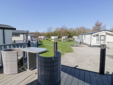 A patio with table and chairs overlooking grass and multiple mobile homes at Lakeside Haven in Carnforth