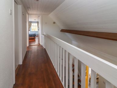 A hallway with wooden flooring leading to a bedroom with a window at Kyleatunna Cottage in Ennis County Clare