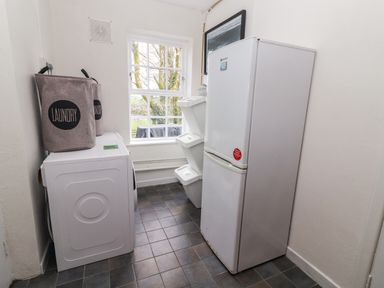 A laundry room with a washing machine laundry bags stacking bins and a refrigerator at Kyleatunna Cottage in Ennis County Clare