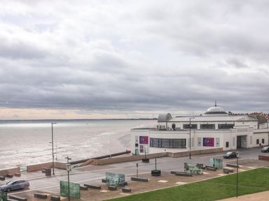 A seafront building near a beach with cloudy sky and parked cars at Apt 3 @ Hunter's Quay in Bridlington