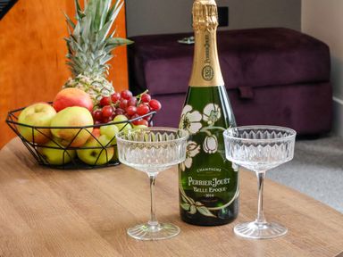 A table with a bottle of Perrier Jouet champagne two glass cups and a fruit basket at Apt 3 @ Hunter's Quay in Bridlington