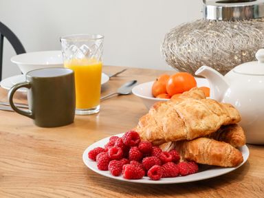 A breakfast table with croissants raspberries orange juice a mug and a teapot at Apt 3 @ Hunter's Quay in Bridlington