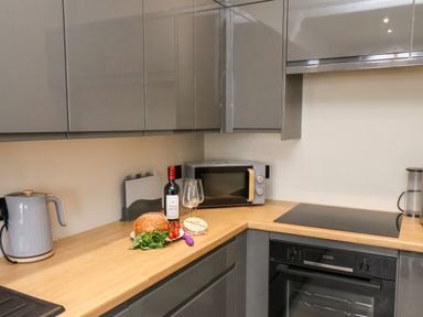 A kitchen countertop with a kettle bread bottle of wine and a microwave at Apt 3 Hunters Quay in Bridlington