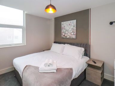 A bedroom with a bed with white linens towels and a painting on the wall at Apt 6 @ Hunter's Quay in Bridlington