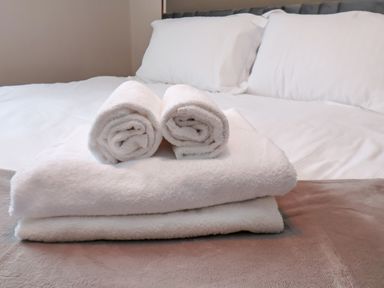 A bed with white pillows and folded white towels at Apt 6 at Hunters Quay in Bridlington