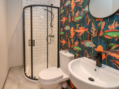 A bathroom with a shower enclosure toilet and sink with fish wallpaper at Apt 6 Hunters Quay Bridlington