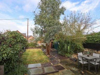 A garden with a lawn a tree shrubs and outdoor dining table at 5 The Crescent in Caernarfon