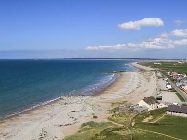 A coastal beach with houses and fields along the shoreline at 5 The Crescent in Caernarfon