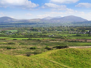 A rural landscape with green fields small houses and hills in the background at 5 The Crescent in Caernarfon