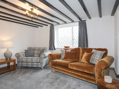 A living room with two sofas a wooden side table and a lamp at 5 The Crescent in Caernarfon