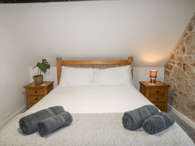 A bedroom with a double bed and two bedside tables with a plant and lamp at 5 The Crescent in Caernarfon