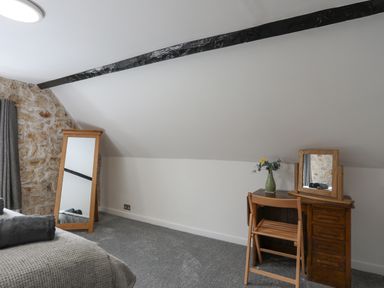 A bedroom with a wooden dressing table, chair, and full-length mirror at 5 The Crescent in Caernarfon