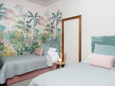 A bedroom with two single beds a wooden side table and tropical wallpaper at Watermouth Castle West Tower Apartment Berrynarbor near Ilfracombe