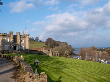 A castle with a lawn and trees at Watermouth Castle, West Tower Apartment in Ilfracombe