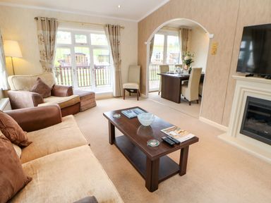 A living room with a coffee table sofa armchair television and fireplace at The Fairhaven in Tunstall near Catterick North Yorkshire