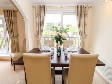 A dining room with a wooden table set with glassware and a flower vase at The Fairhaven in Tunstall near Catterick North Yorkshire