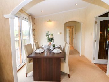 A dining room with a dark wooden table set with plates glasses and a flower vase at The Fairhaven in Tunstall near Catterick North Yorkshire