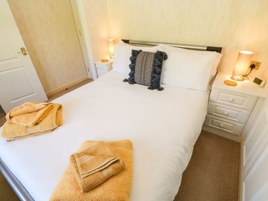 A bedroom with a bed white bedding bedside tables lamps and towels at The Fairhaven in Tunstall near Catterick North Yorkshire