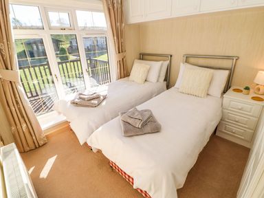 A bedroom with two single beds and a nightstand by a window at The Fairhaven in Tunstall near Catterick North Yorkshire