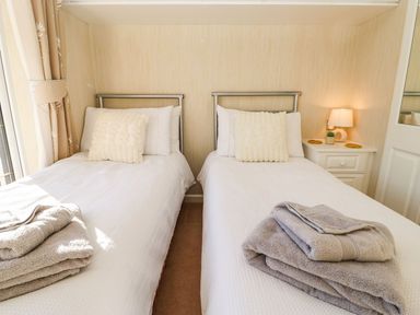A bedroom with two single beds with towels on them and a nightstand with a lamp at The Fairhaven in Tunstall near Catterick North Yorkshire