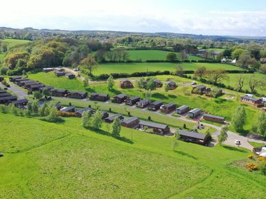 Aerial view of a holiday park with multiple wooden lodges and green fields at The Fairhaven in Tunstall near Catterick North Yorkshire