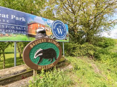 A sign with a badger carving and the words Badgers Retreat Welcome by a billboard for Wyldecrest Parks surrounded by trees and grass at The Fairhaven in Tunstall near Catterick North Yorkshire