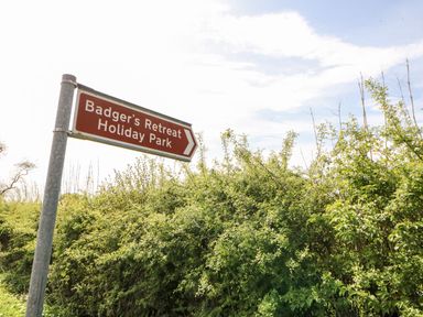A road sign for Badger's Retreat Holiday Park next to green bushes and blue sky