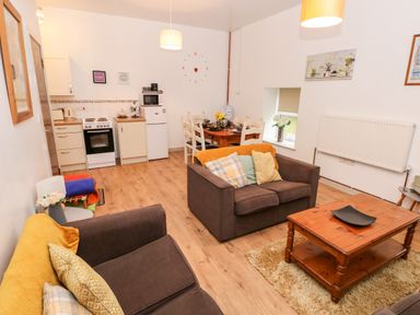 A living room and kitchen area with couches, coffee table, dining table, and appliances at Barn 2 in Ystradgynlais