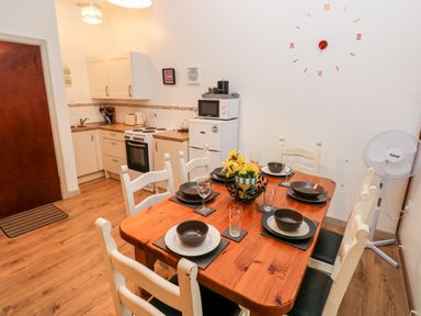 A kitchen and dining area with a wooden table set for six with plates and glasses at Barn 2 Ystradgynlais