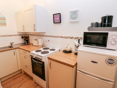 A kitchen with a sink stove refrigerator microwave and cabinets at Barn 2 in Ystradgynlais
