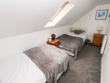 A bedroom with two single beds side by side a skylight and wooden bedside tables at Barn 2 in Ystradgynlais